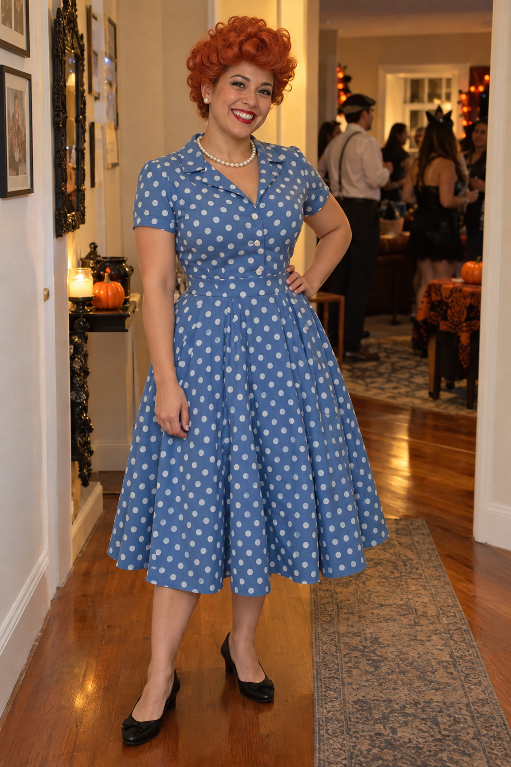 Partygoer wearing a blue polka-dot dress, pearls and a curled red updo