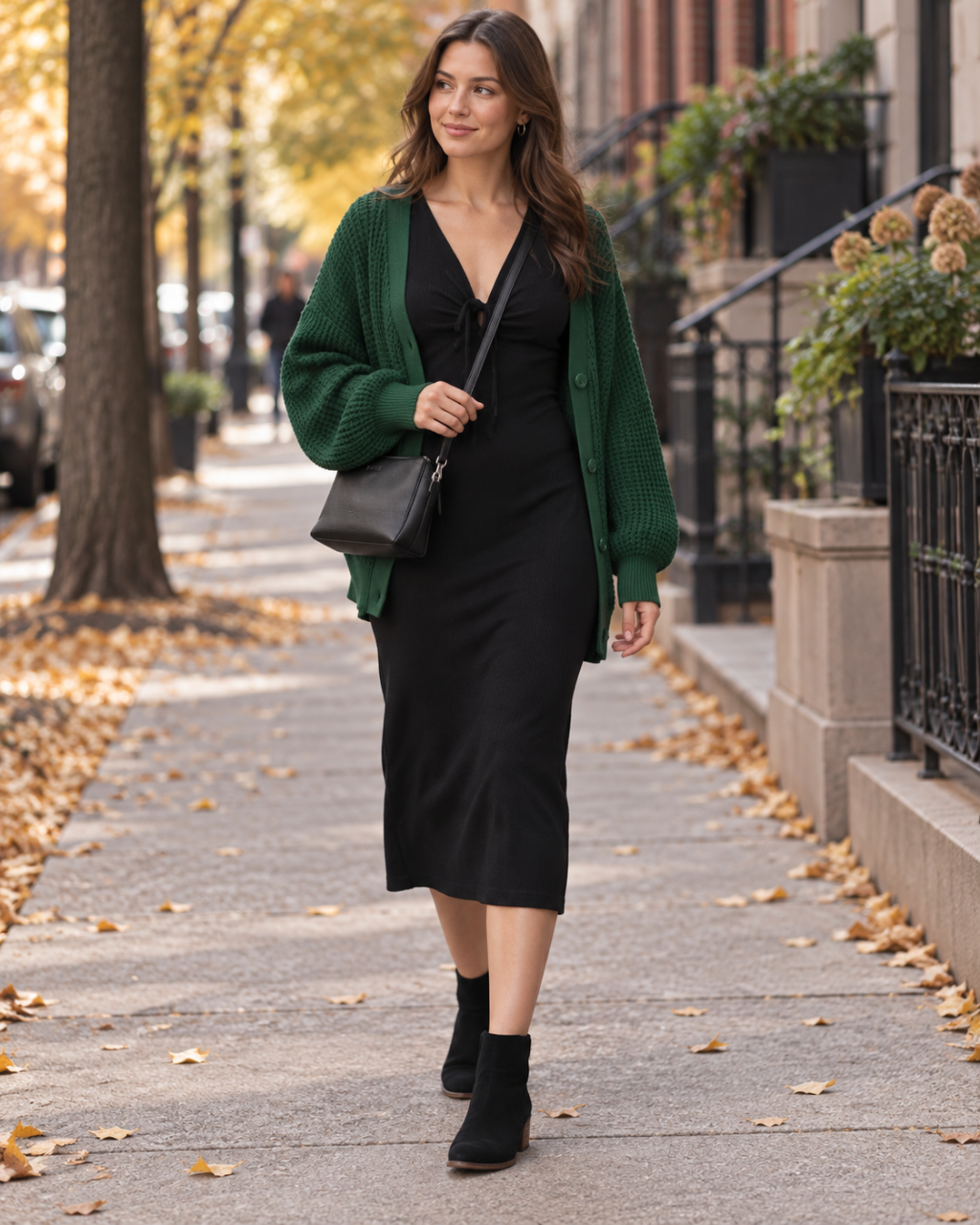 Adult wearing an emerald cardigan over a black midi dress with black ankle boots