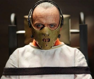 Masked Hannibal Lecter in the pale costume jacket and orange jumpsuit